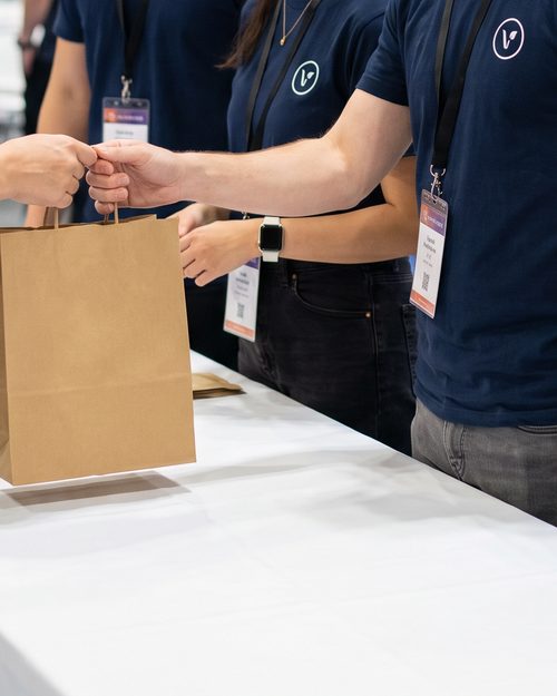 Personal de un evento con camisetas azul marino entregando una bolsa